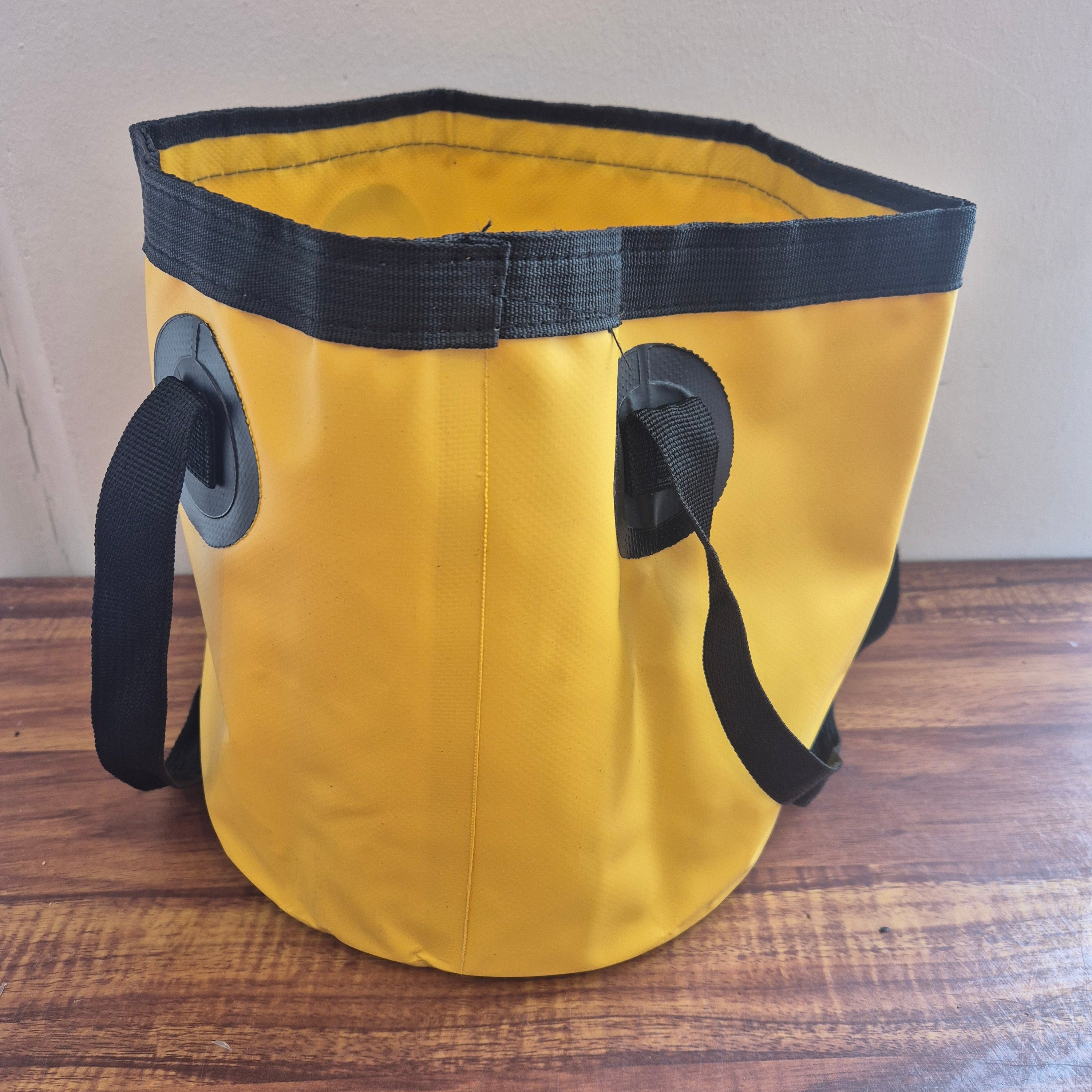 Yellow bag with black straps on a wooden surface